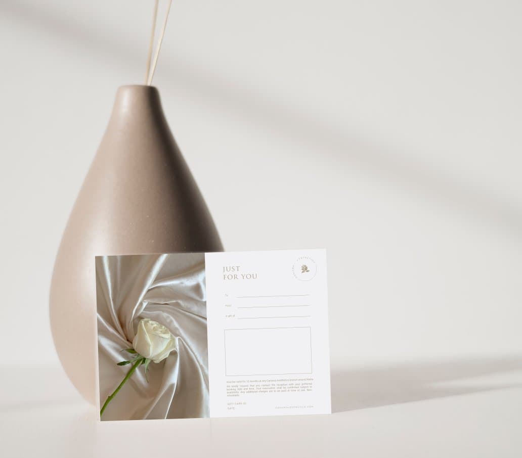 A Carisma Aesthetics gift card presented on a studio table