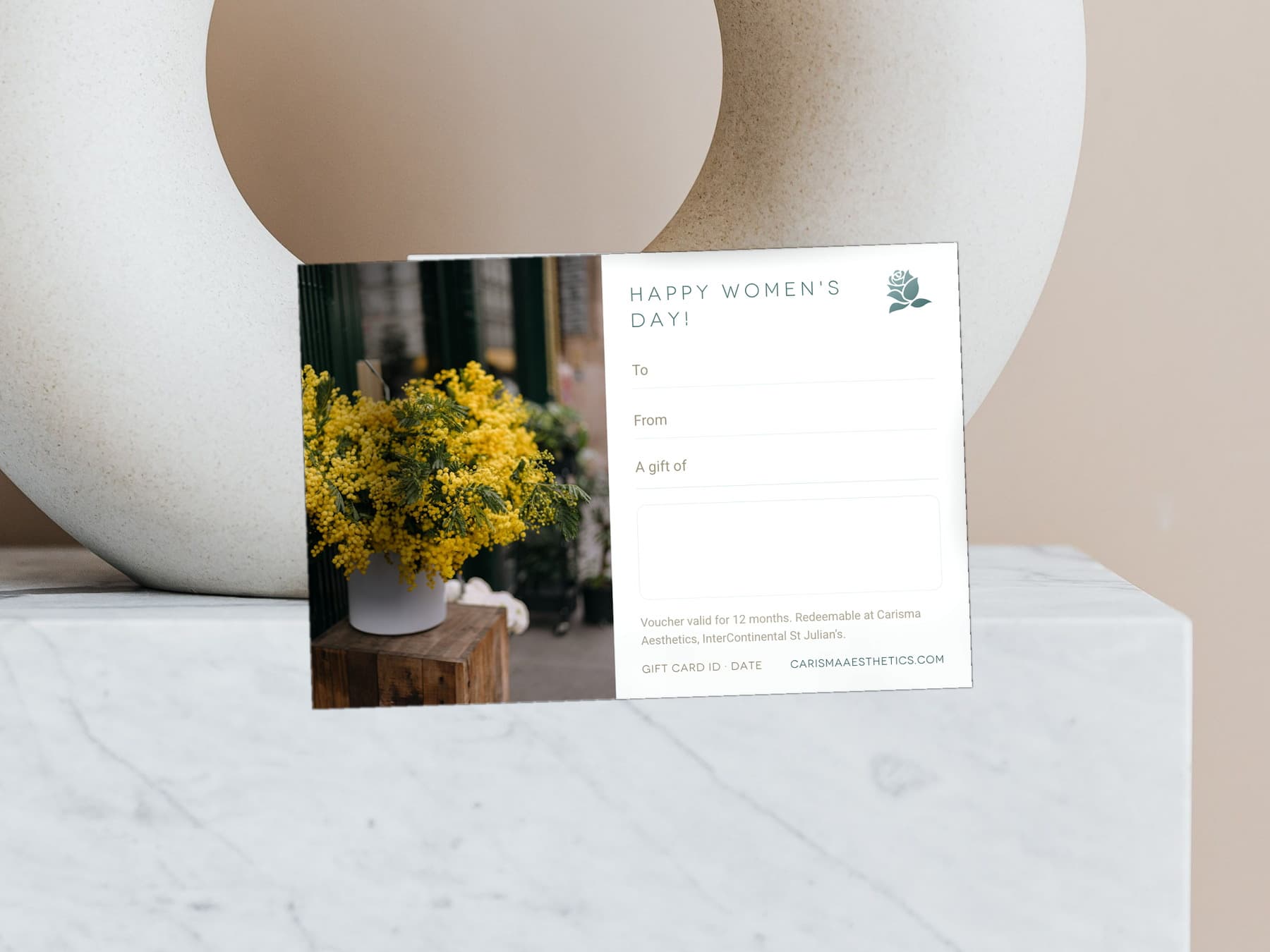 A Carisma Aesthetics Women's Day gift card with mimosa and lilac on pale stone